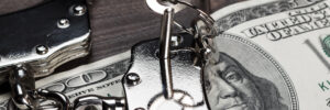 handcuffs with a key sitting on 100 dollar bill